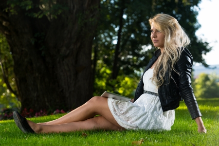 Pretty Woman Sitting On The Grass With Digital Tabletの写真素材