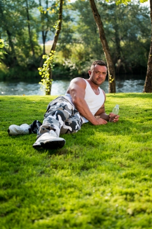 Man Lying On Grass And Holding Bottle Of Waterの写真素材