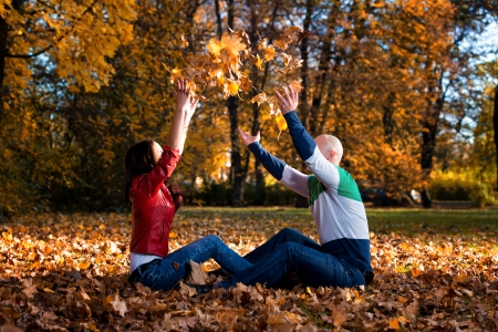 Loving Couple Toss The Leaves In Autumn Parkの写真素材