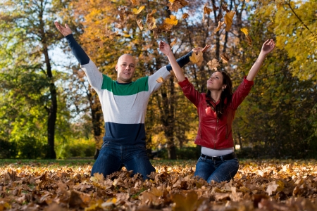 Loving Couple Toss The Leaves In Autumn Parkの写真素材