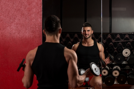 Young Man Lifting Dumbbell In Gymの写真素材