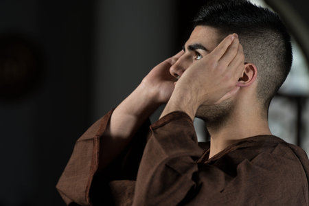 Young Muslim Man Making Traditional Prayer To God While Wearing A Traditional Cap Djellaba