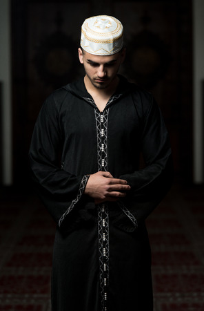 Young Muslim Guy Making Traditional Prayer To God While Wearing A Traditional Cap Dishdashaの写真素材