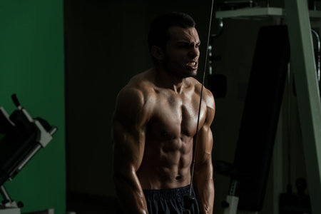 Young Man Exercise In The Gym - He Is Performing Two Arm Triceps Push Downs