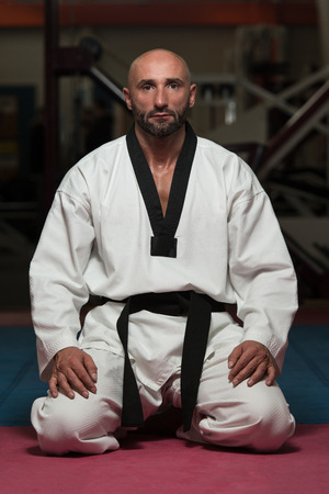 Black Belt Karate Man Sit On A Position To Start Or Finish Practicingの写真素材