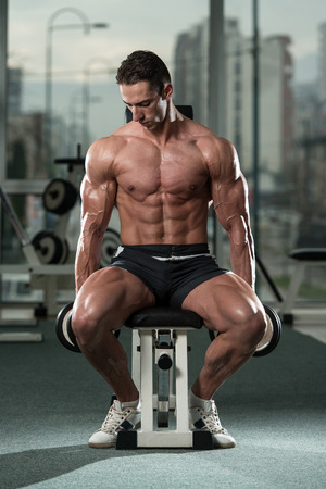 Young Man Working Out Biceps - Dumbbell Concentration Curlsの写真素材