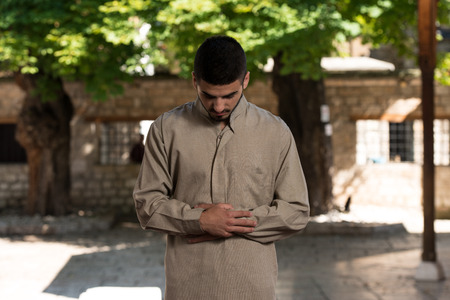 Young Muslim Man Making Traditional Prayer To God While Wearing A Traditional Cap Dishdashaの写真素材
