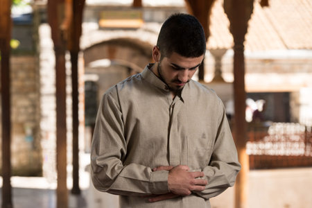 Young Muslim Man Making Traditional Prayer To God While Wearing A Traditional Cap Dishdasha