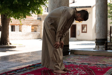 Young Muslim Man Making Traditional Prayer To God While Wearing A Traditional Cap Dishdasha