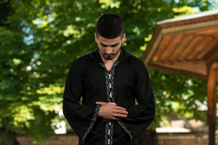 Young Muslim Man Making Traditional Prayer To God While Wearing A Traditional Cap Dishdasha
