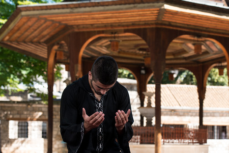 Young Muslim Man Making Traditional Prayer To God While Wearing A Traditional Cap Dishdashaの写真素材