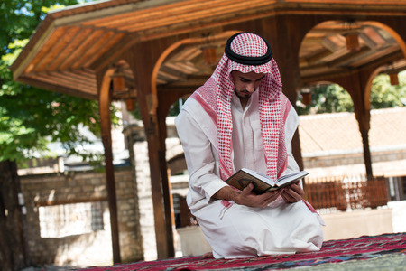 Young Muslim Man Making Traditional Prayer To God While Wearing A Traditional Cap Dishdashaの写真素材