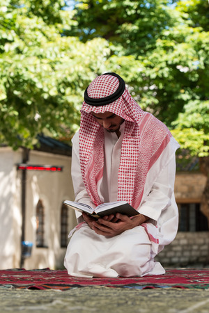 Young Muslim Man Making Traditional Prayer To God While Wearing A Traditional Cap Dishdashaの写真素材