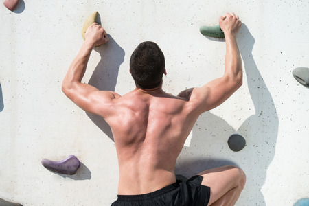 Young Man Climbs Up An Outdoors Rock Wall - He Is Clearly Determined To Make It To The Topの写真素材