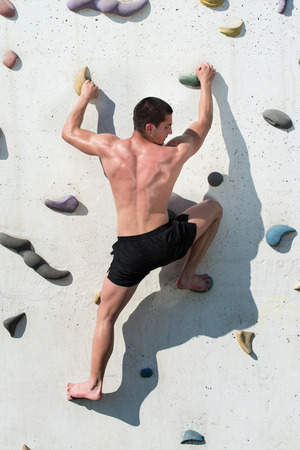 Young Man Climbs Up An Outdoors Rock Wallの写真素材