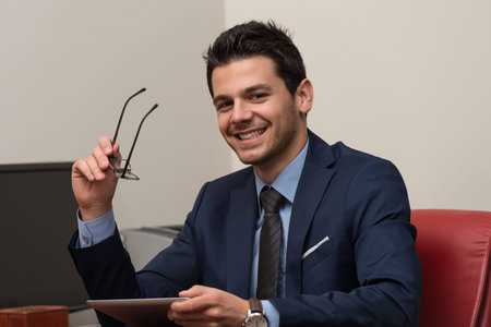 Portrait Of A Young Business Man Using A Touchpad In The Office