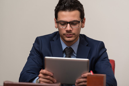 Portrait Of A Young Business Man Using A Touchpad In The Officeの写真素材