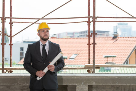 Portrait Of Construction Master With Yellow Helmet And Blueprint In Hands