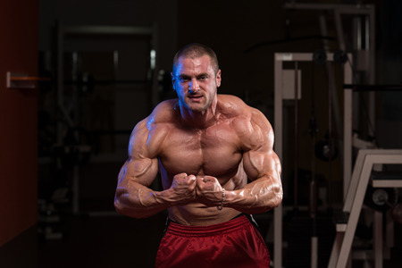 Serious Bodybuilder Standing In The Gym And Flexing Musclesの写真素材