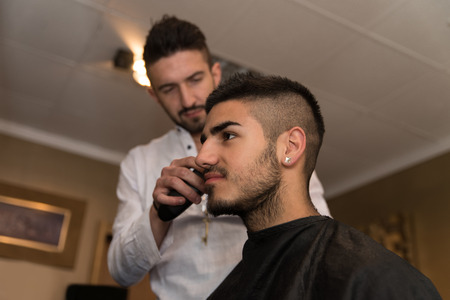 Handsome Young Hairdresser Giving A New Haircut To Male Customer At Parlorの写真素材