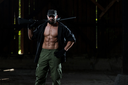 Action Hero Muscled Man Holding Machine Gun - Standing In Abandoned Building Wearing Green Pantsの写真素材