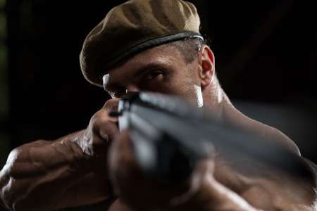 Action Hero Muscled Man Holding Machine Gun - Standing In Abandoned Building Wearing Green Pantsの写真素材