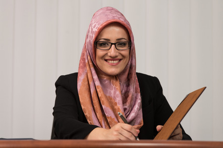Muslim Businesswoman Writing A Letter - Notes Or Correspondence Or Signing A Document Or Agreementの写真素材