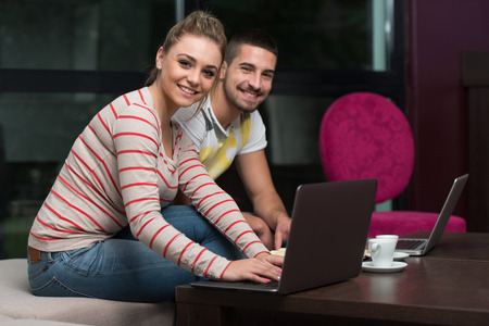 Two Beautiful Students Drinking And Having Fun With Laptop In Cafeteriaの写真素材