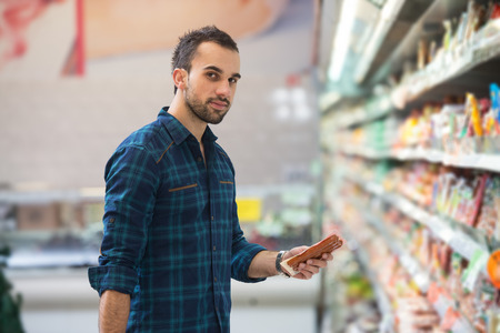 Handsome Young Man Shopping For Fruits And Vegetables In Produce Department Of A Grocery Store - Supermarket - Shallow Deep Of Fieldの写真素材