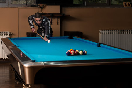 Young Man Lining To Hit Ball On Pool Table