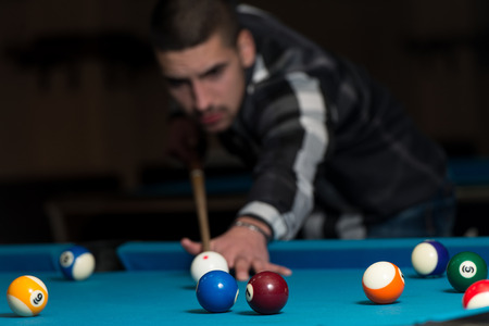 Young Man Lining To Hit Ball On Pool Tableの写真素材