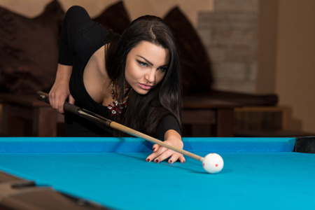 Young Woman Lining To Hit Ball On Pool Tableの写真素材