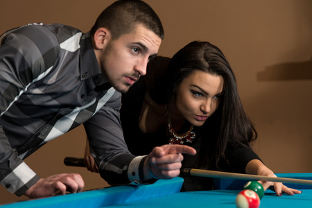 Young Caucasian Woman Receiving Advice On Shooting Pool Ball While Playing Billiardsの写真素材