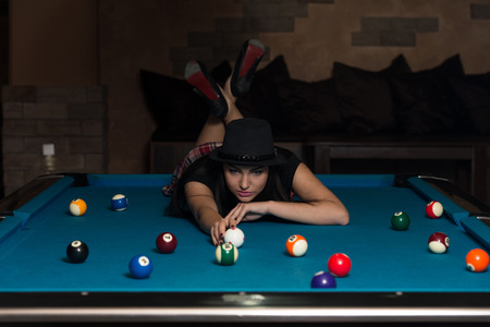 Portrait Of A Young Woman Lying On The Table And Playing Billiardsの写真素材