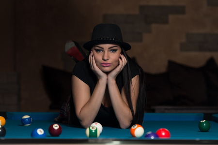 Portrait Of A Young Woman Lying On The Table And Playing Billiardsの写真素材