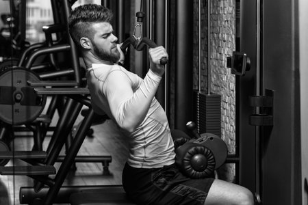 Young Man Doing Heavy Weight Exercise For Back In Gym