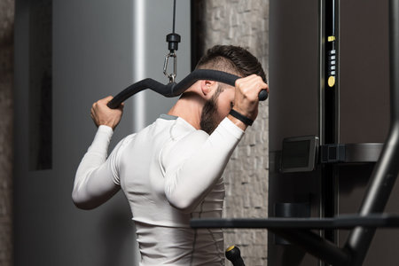 Young Man Doing Heavy Weight Exercise For Back In Gym