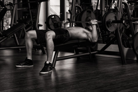 Handsome Man Is Working Out Chest With Barbell In A Modern Gym