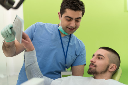 Dentist , Assistant And Patient Looking At Tooth X-Rayの写真素材