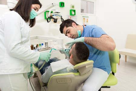 Male Patient With Dentist And Assistant In A Dental Treatment - Wearing Masks And Glovesの写真素材