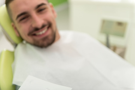 Happy Smiling Patient Says Personal Information While The Dentist Writes On The Cardの写真素材