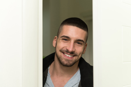 Young Man Entering Through His Front Door With A Smile On His Faceの写真素材