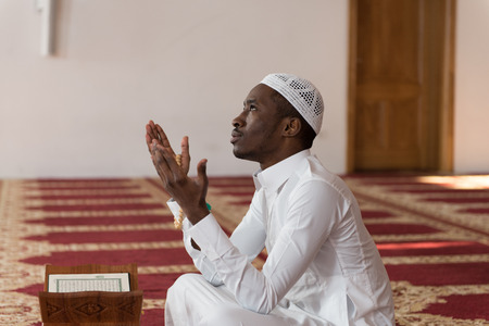 African Muslim Man Making Traditional Prayer To God While Wearing A Traditional Cap Dishdashaの写真素材