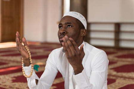 African Muslim Man Making Traditional Prayer To God While Wearing A Traditional Cap Dishdashaの写真素材