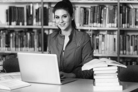 In The Library - Pretty Female Student With Laptop And Books Working In A High School Or University...