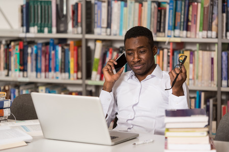 African Male Student Talking On The Phone In Library - Shallow Depth Of Fieldの写真素材