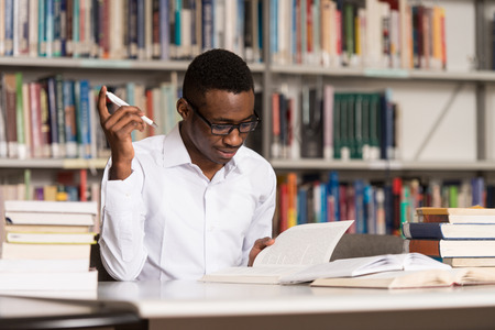 Portrait Of African Clever Student With Open Book Reading It In College Library - Shallow Depth Of Fieldの写真素材