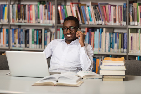African Male Student Talking On The Phone In Library - Shallow Depth Of Fieldの写真素材