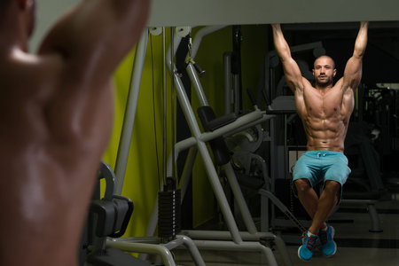 Young Man Performing Hanging Leg Raises Exercise - One Of The Most Effective Ab Exercises