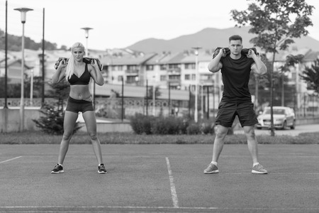 A Group Of Young People In Aerobics Class Performing Bag Squat Exercise Outdoorの写真素材